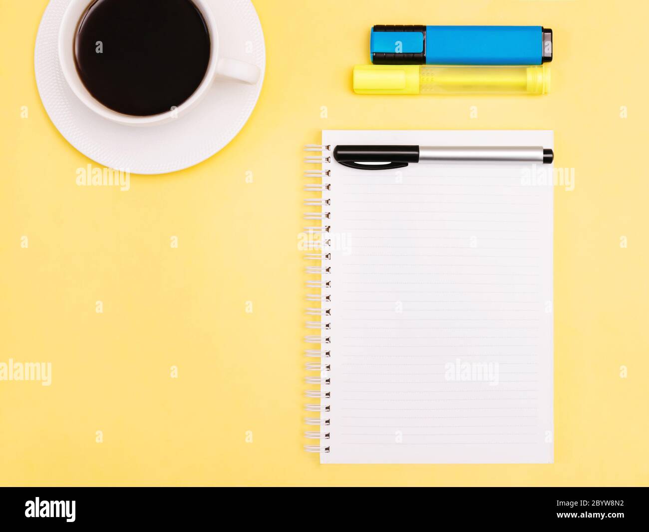 Planner primo piano foto in alto blocco note, pennarelli colorati e tazza di caffè nero su sfondo giallo Foto Stock