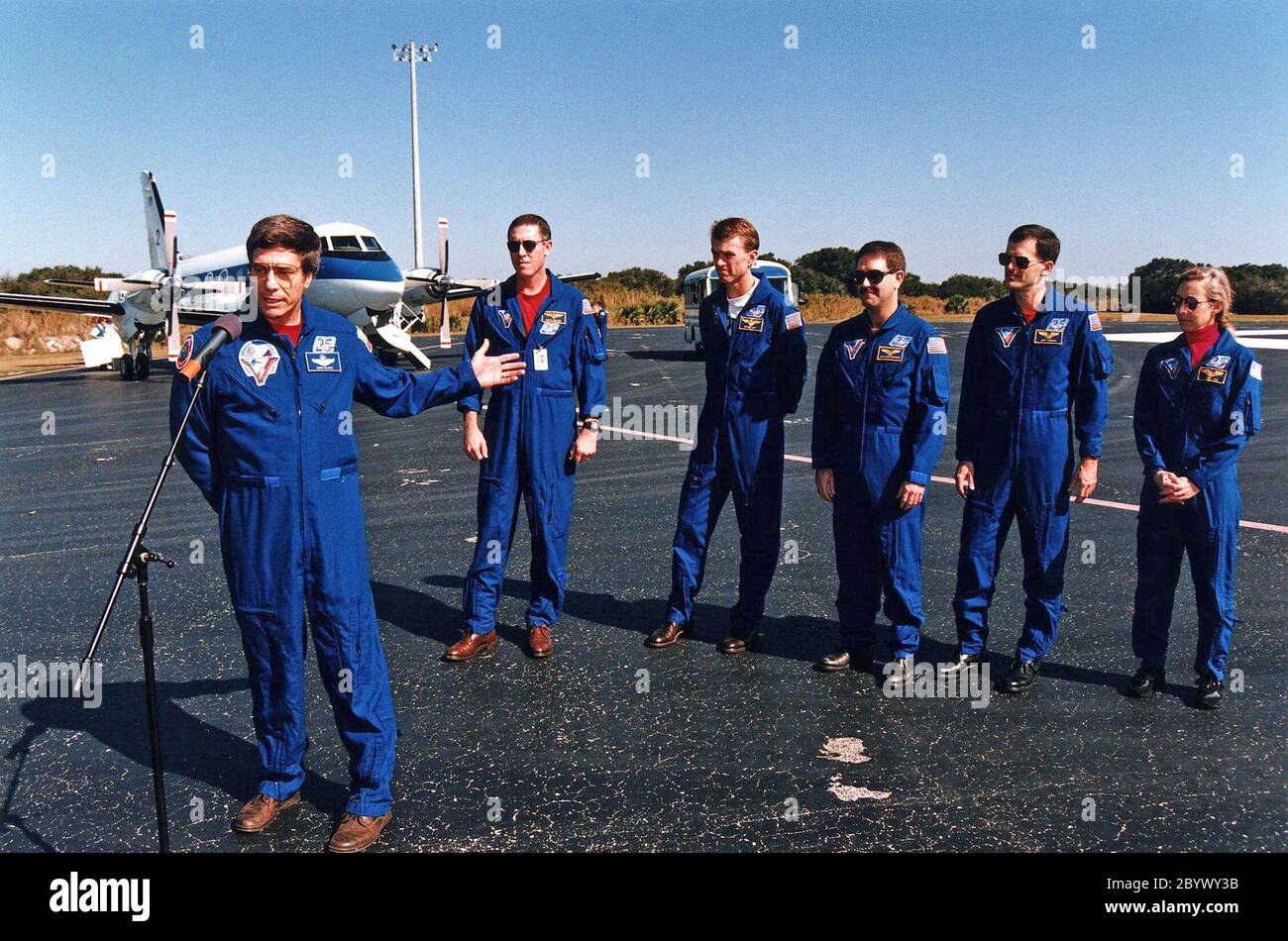 Ritorno astronauta della NASA ed ex membro dell'equipaggio Mir 22 John E. Blaha (a sinistra), gesti verso i suoi compagni membri dell'equipaggio STS-81 durante una conferenza stampa prima della loro partenza per Johnson Space Center dal gennaio 23 dalla Skid Strip presso la stazione aerea di Cape Canaveral. L'equipaggio è arrivato al KSC a bordo dello Space Shuttle Atlantis il 22 gennaio per concludere la quinta missione di attracco dello Shuttle-Mir e tornare a Blaha sulla Terra dopo quattro mesi nello spazio. Dietro Blaha da sinistra ci sono il comandante della missione Michael A. Baker; il pilota Brent W. Jett, e gli specialisti della missione John M. Grunsfeld, Peter J. K. 'Jeff' Wisoff e Marsha S. Foto Stock