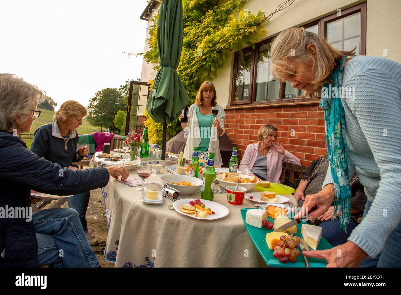 Riunione di club di libri di divaricamento sociale nel giardino dei soci nel Regno Unito Foto Stock