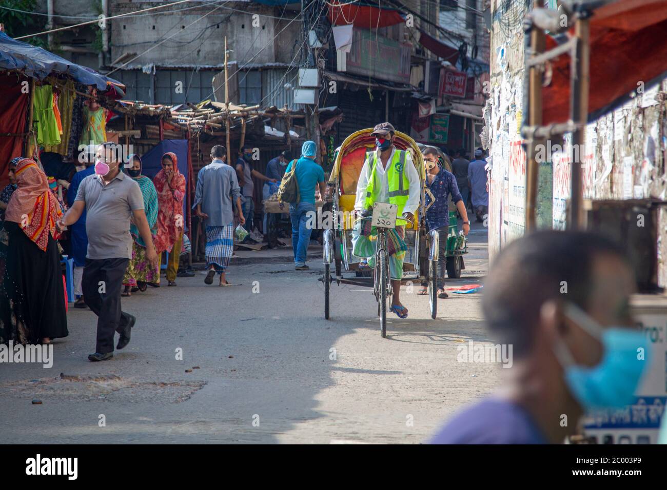Persone che indossano maschere in una strada nel quartiere Baridhara di Dhaka. Nel tentativo di fermare la diffusione della malattia di COVID-19, il governo del Bangladesh sta introducendo zone di blocco nelle aree con infezioni da sars-2. Foto Stock