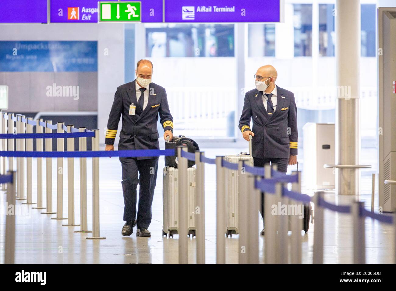 I piloti che indossano maschere facciali stanno camminando attraverso l'aeroporto di Francoforte quasi vuoto durante il blocco causato dal virus COVID-19. In tutto il mondo, il settore del traffico aereo è fortemente influenzato dal massiccio calo del traffico. Foto Stock