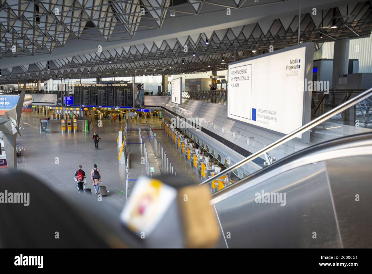 Passeggeri nell'area di check-in dell'aeroporto di Francoforte quasi vuoto durante il blocco causato dal virus COVID-19. In tutto il mondo, il settore del traffico aereo è fortemente influenzato dal massiccio calo del traffico. Foto Stock