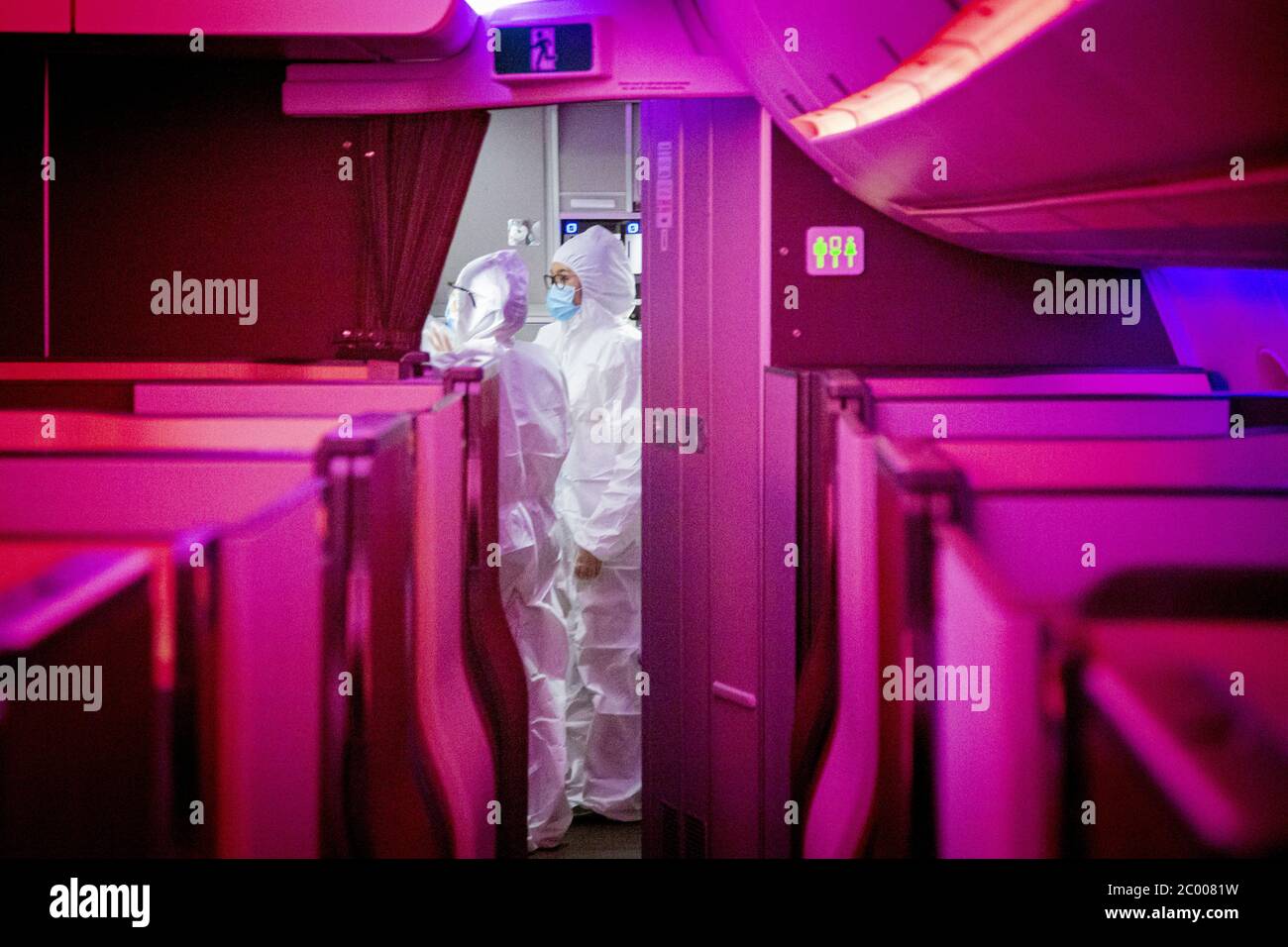 I commissari di aria in completo equipaggiamento haz-MAT a bordo di un volo Qatar Airways stanno preparando i pasti a bordo durante il blocco causato dal virus COVID-19. Qatar Airways ha adottato misure di sicurezza rigorose per poter volare missioni specializzate durante la pandemia. In tutto il mondo, il settore del traffico aereo è fortemente influenzato dal massiccio calo del traffico. Foto Stock