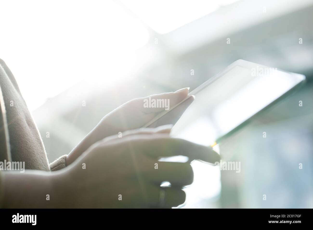 Donna che utilizza un tablet PC contro la luce diretta del sole Foto Stock