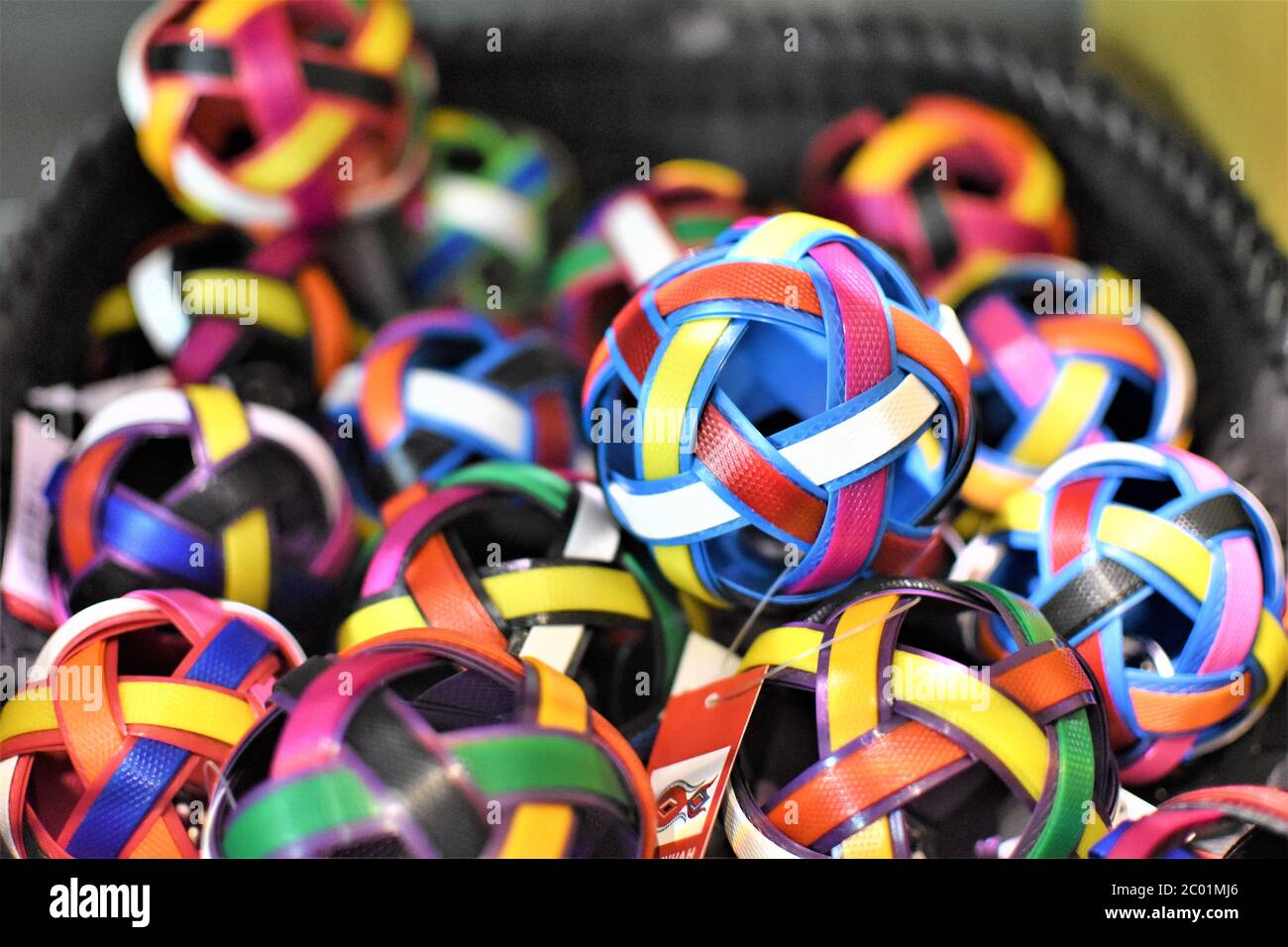Un mucchio di palline decorative in vimini fatte a mano in diversi colori luminosi sono sparse in un cesto Foto Stock