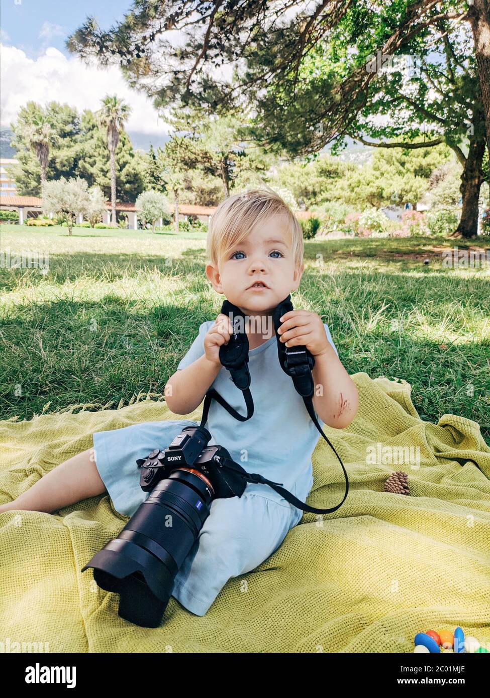 Budva, Montenegro - 10 giugno 2020: Una bambina si trova in un parco su una plaid, con una fotocamera a7III Sony e 35mm f1.4 Carl Zeiss intorno al collo. Foto Stock