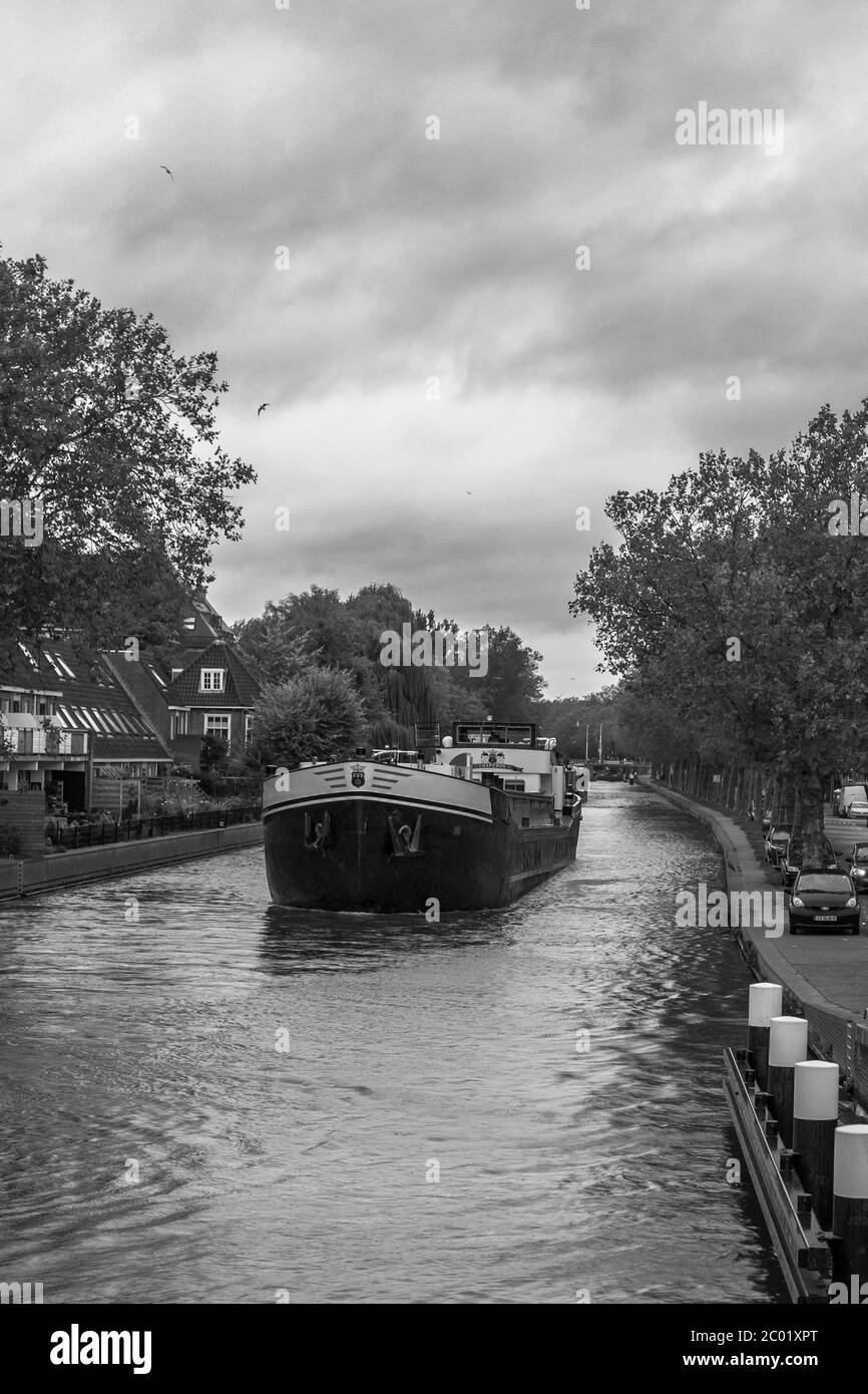Chiatta che naviga lungo il Rijn-Schiekanaal a Delft, e che si avvicina al Ponte Koepoort, Delft, Sud Olanda, Paesi Bassi. Versione in bianco e nero Foto Stock