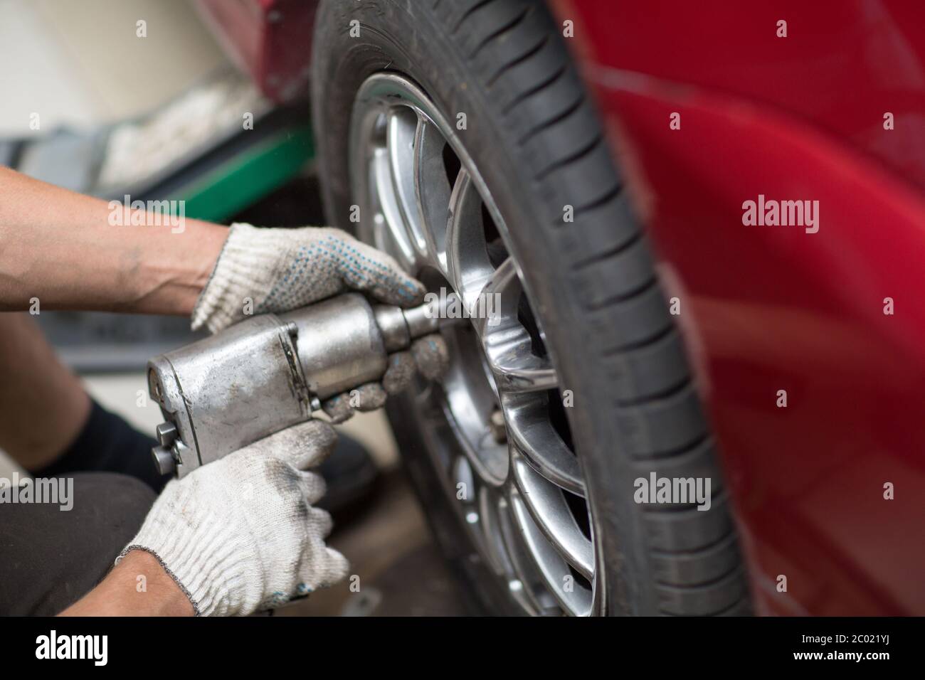 Riparazione o sostituzione del macchinone del veicolo avvitatura della ruota dell'auto presso la stazione di servizio di riparazione. Foto Stock