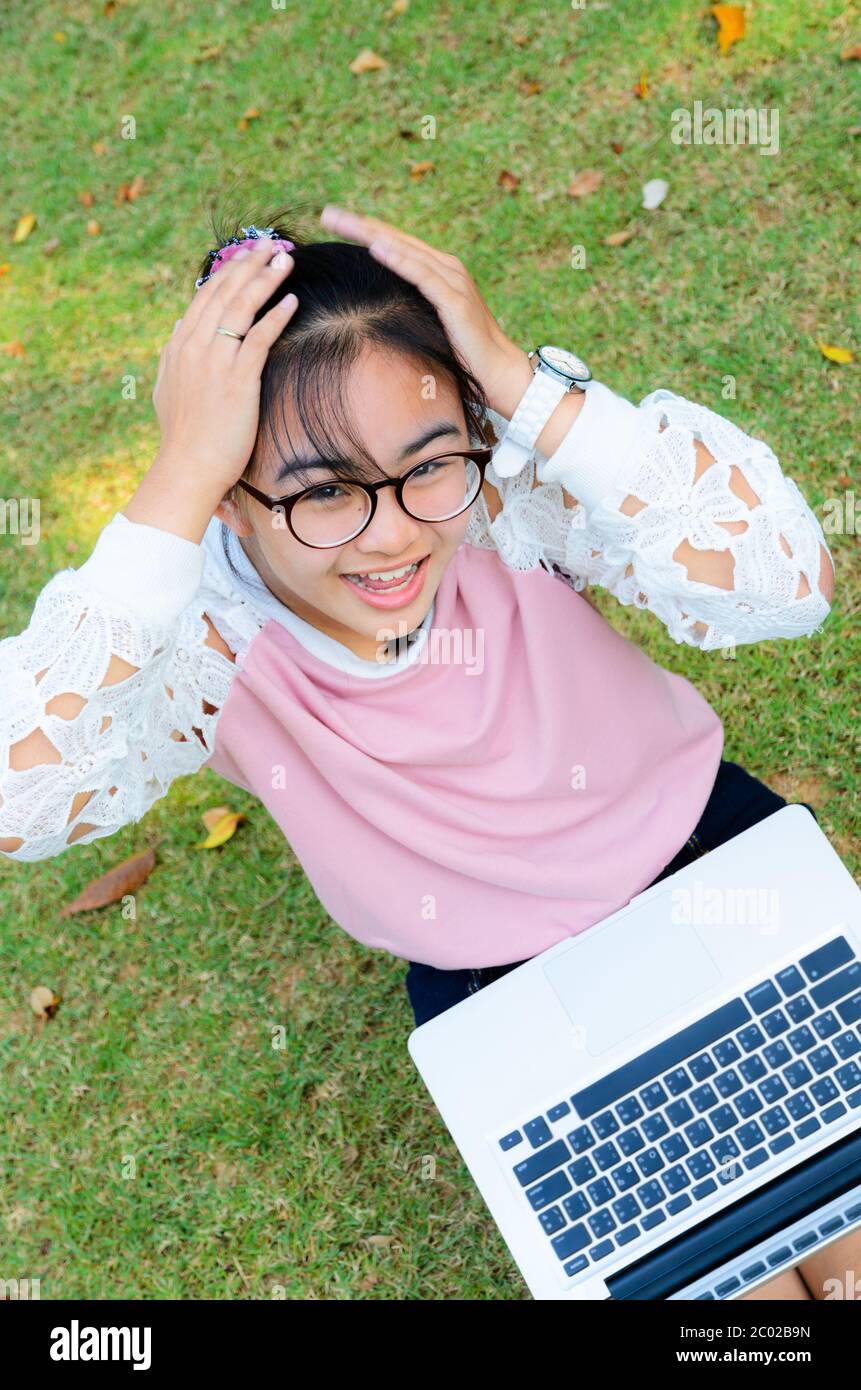 Ragazza carina è felice con notebook su erba Foto Stock