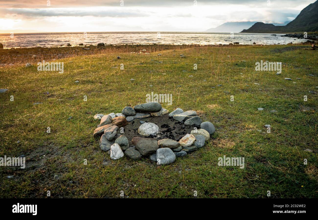 Fuoco di campo sulla spiaggia durante un tramonto estivo vibrante. Preso il punto più a nord della penisola di Lyngen, Lyngen, Norvegia Foto Stock