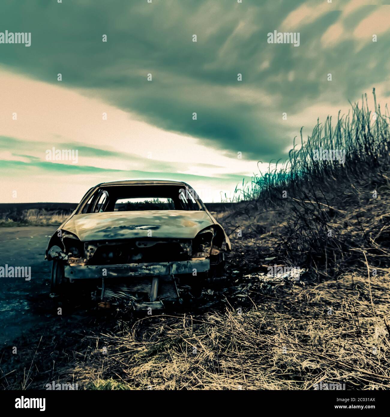 Auto abbandonata sul lato della strada con erba, pozzanghere e cielo - 'fine della strada' Foto Stock