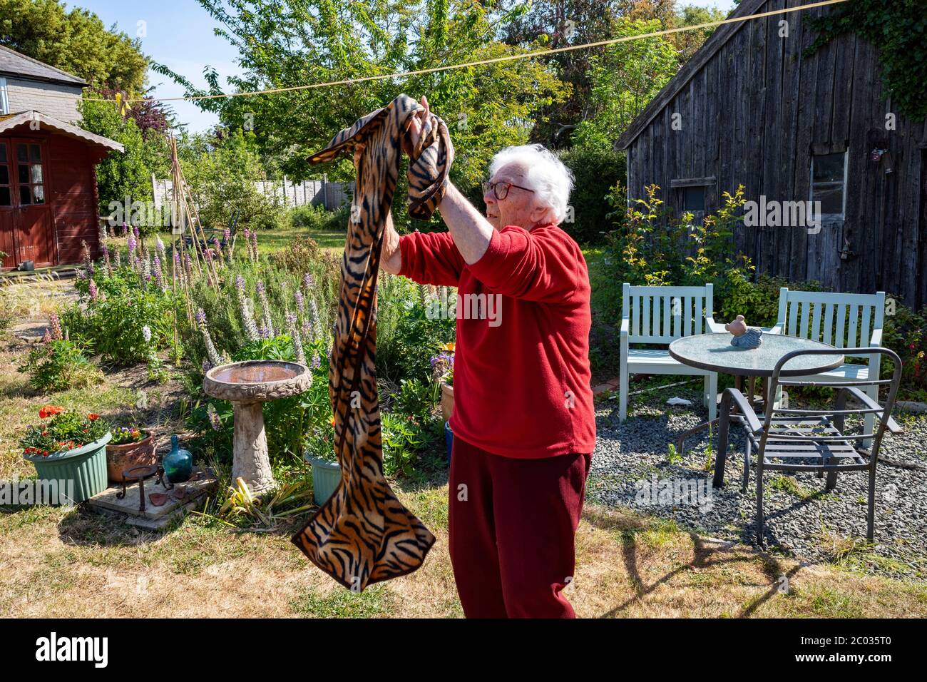 donna di 90 anni che vive da sola appesa fuori lavando ad asciugare Foto Stock