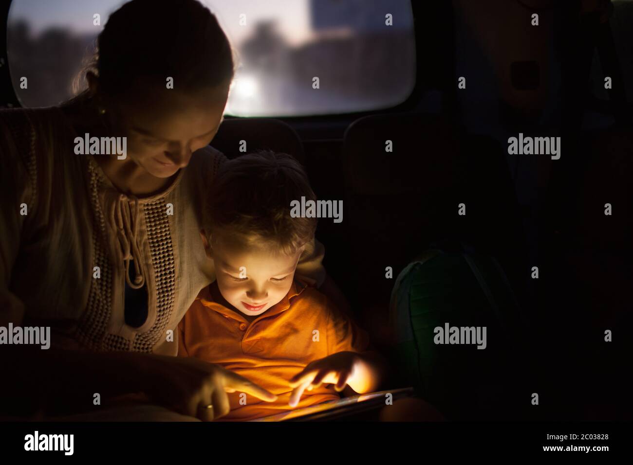 Madre e Figlio con pad durante il viaggio in auto di notte Foto Stock