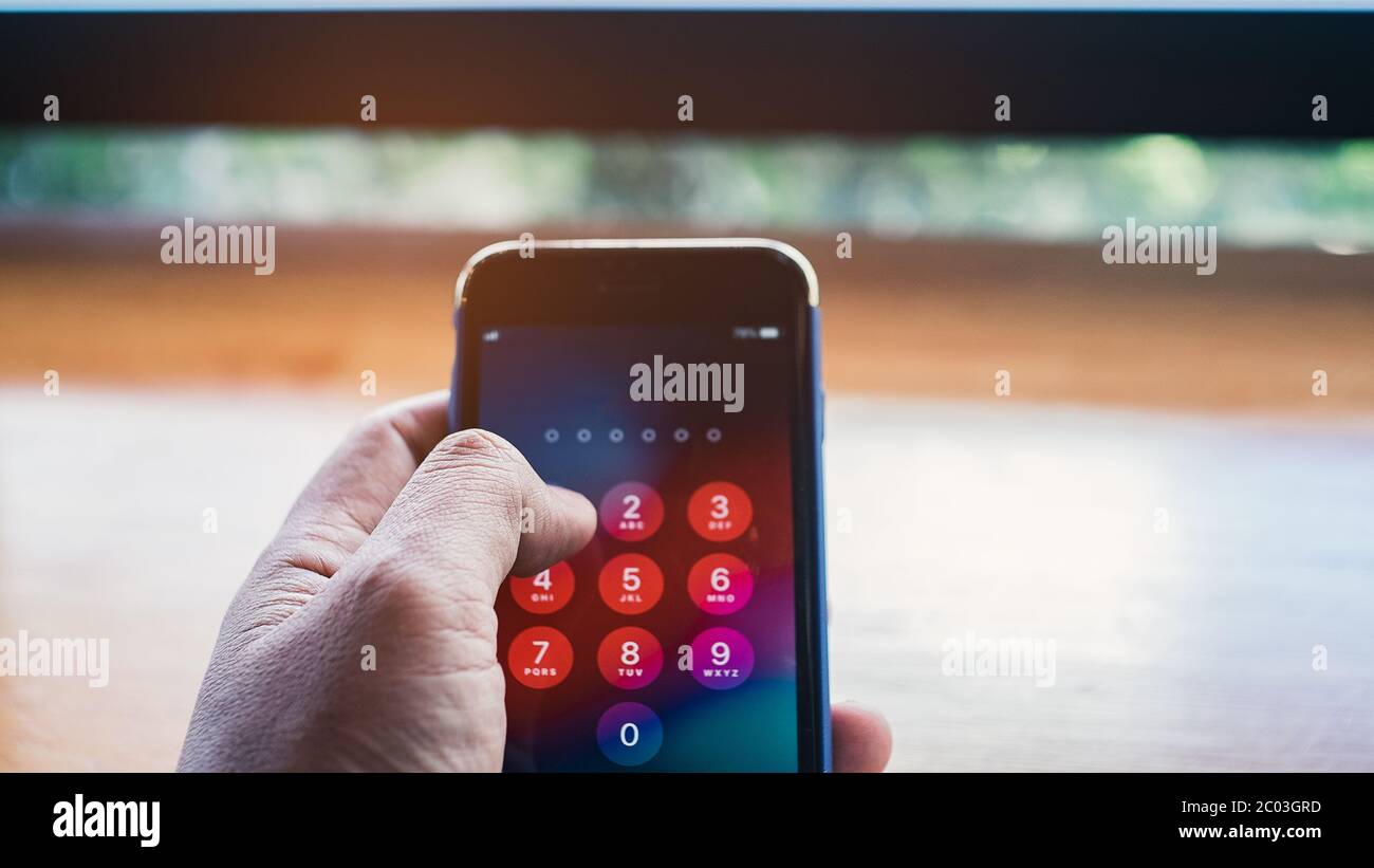 Tenere lo smartphone mentre si inserisce il codice password Foto Stock