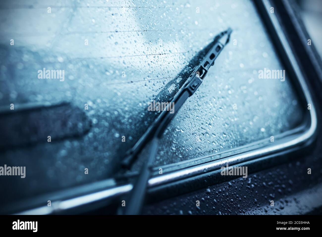 Tergicristallo nero sul lunotto di un'autovettura, coperto da gocce di pioggia torrenziale in condizioni meteorologiche avverse molto nuvolose. Foto Stock Tergicristallo nero sul lunotto di un'autovettura, coperto da gocce di pioggia torrenziale in condizioni meteorologiche avverse molto nuvolose. Foto Stock