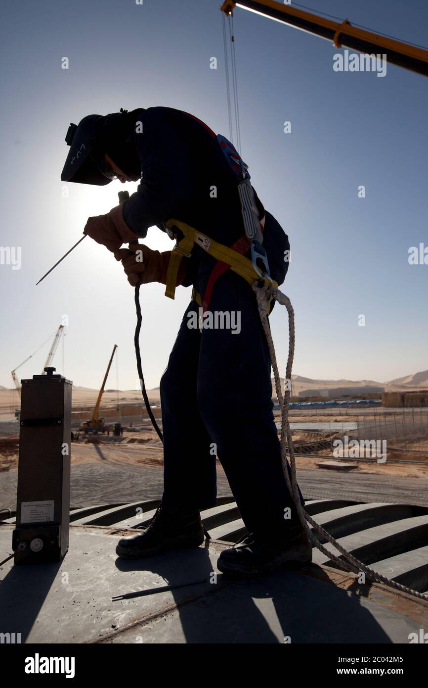 Un saldatore si prepara a fissare piastre in acciaio a un recipiente a pressione in un nuovo impianto petrolifero nel deserto del Sahara. Foto Stock