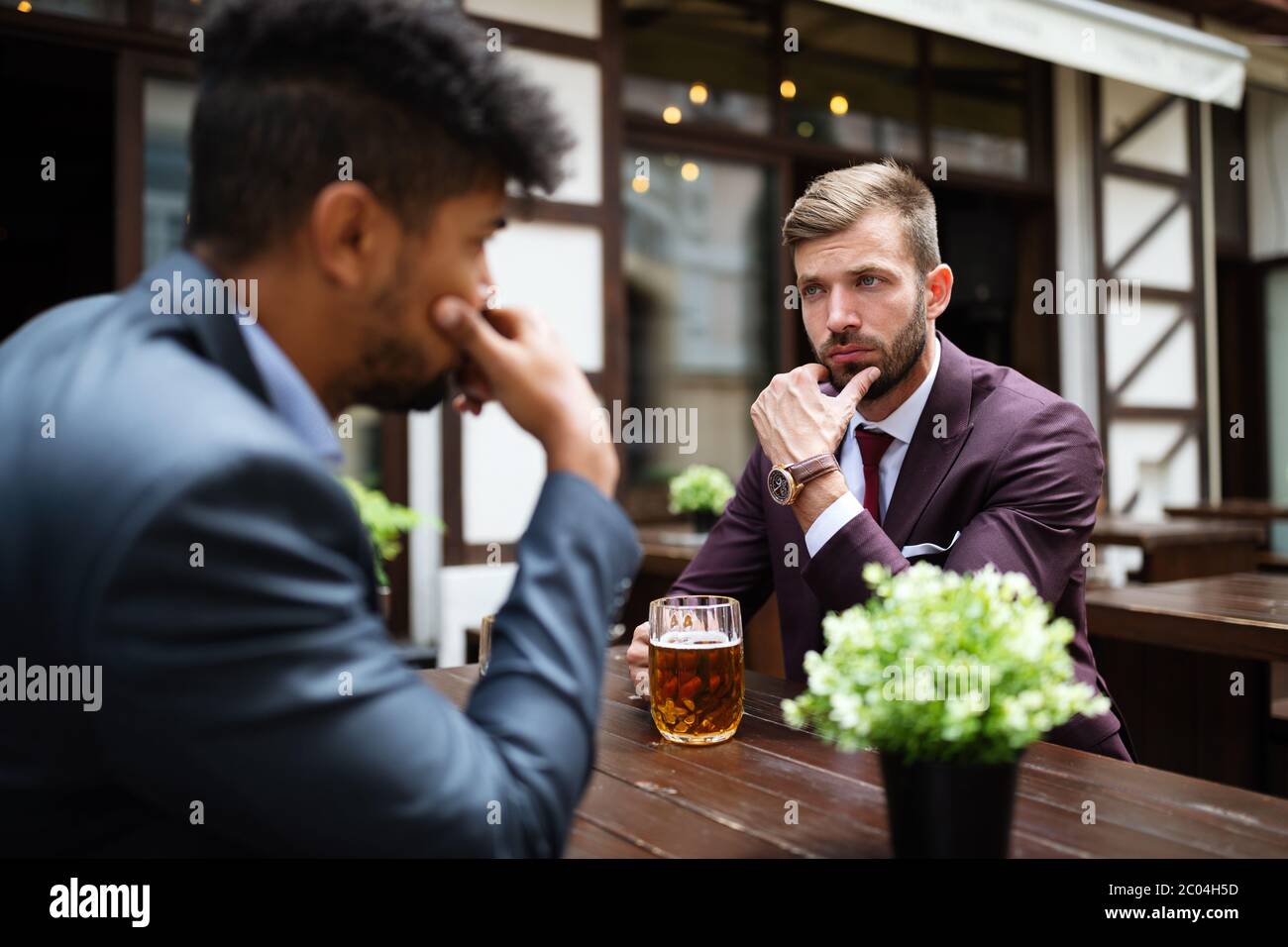 Due uomini d'affari scettici che parlano in una riunione all'aperto Foto Stock