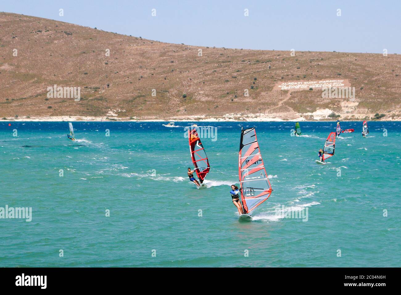 Giovane donna che guida la formazione corre durante i preparativi per il PWA World Tour Windsurf Competition ad Alacati. Foto Stock