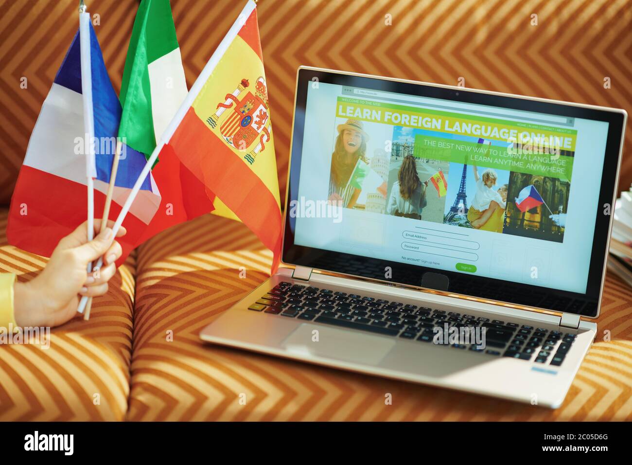 Primo piano su donna con bandiere imparare lingua straniera online su un computer portatile a casa in giornata di sole. Foto Stock
