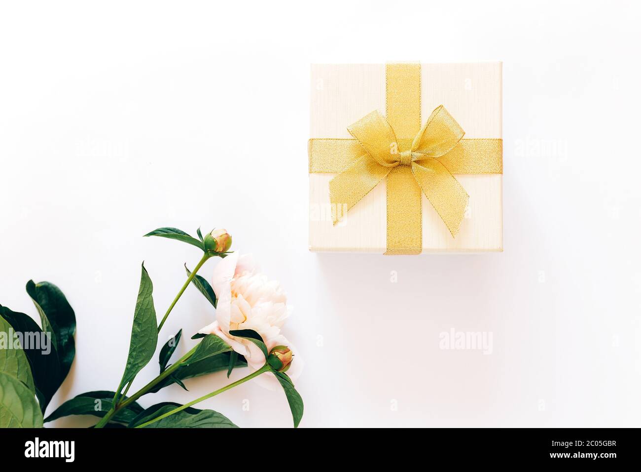 Bel bouquet di peonie e una scatola bianca con un arco giallo su sfondo bianco, peonie fiorite Foto Stock