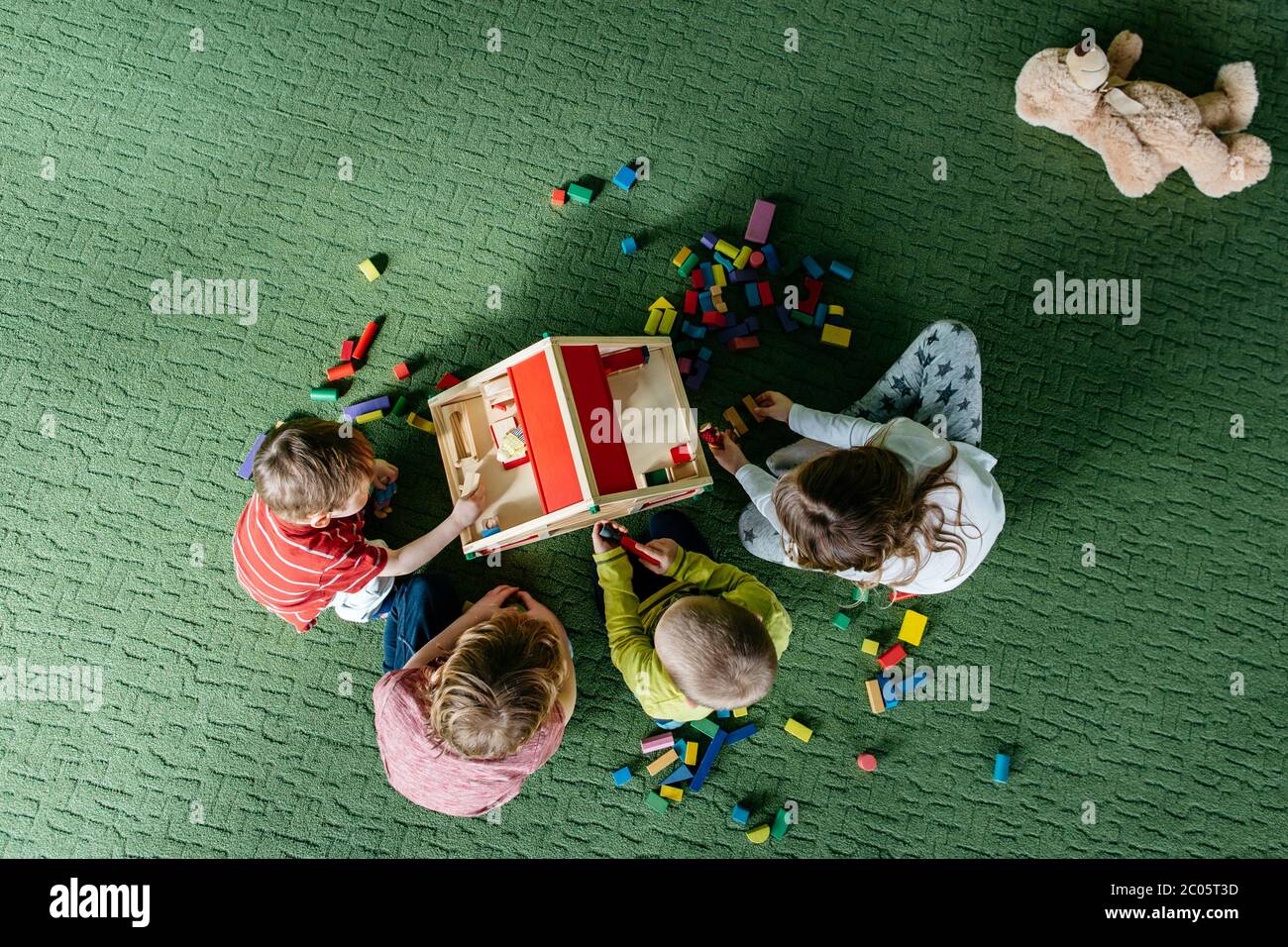 Vista dall'alto dei bambini che giocano con una casa di bambola in legno Foto Stock