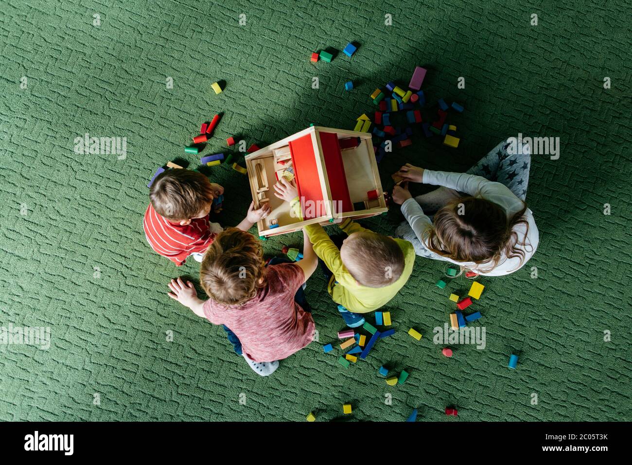 Vista dall'alto dei bambini che giocano insieme a una casa di bambola in legno Foto Stock