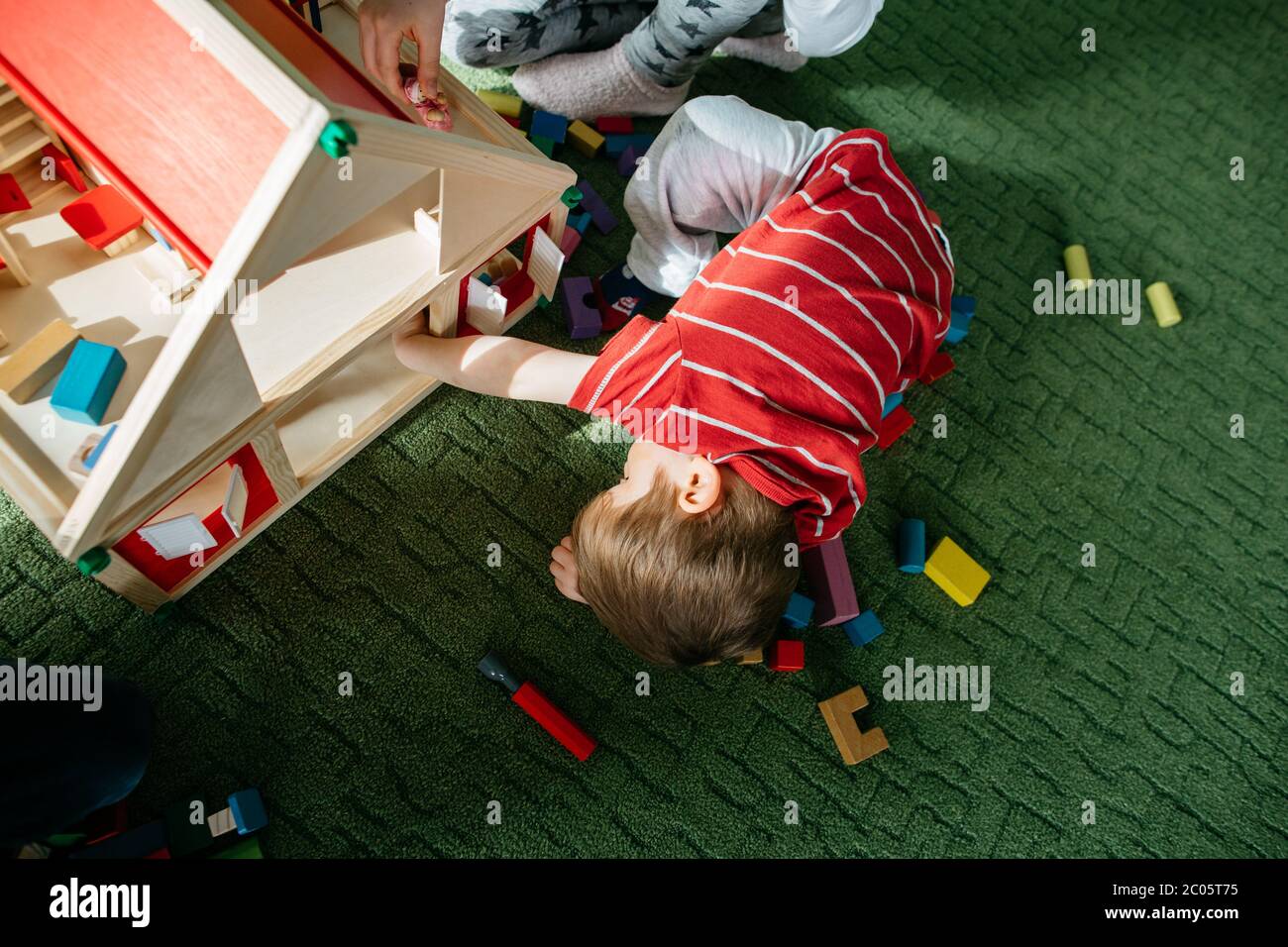 Vista dall'alto di un bambino che gioca con una casa di bambola in legno Foto Stock