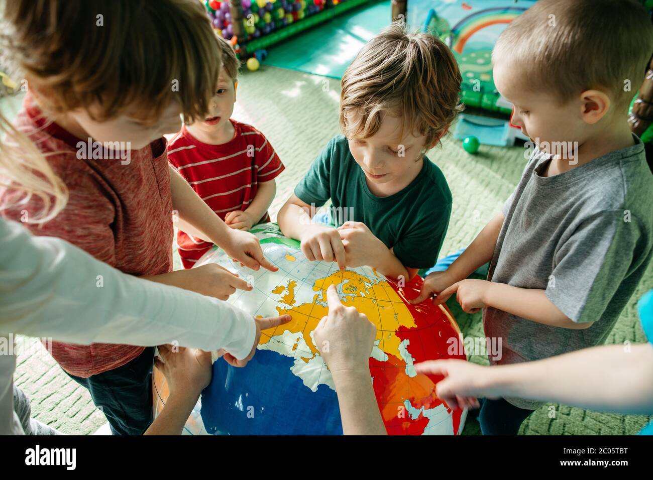 Bambini che imparano circa i paesi con una sfera del globo gonfiabile Foto Stock