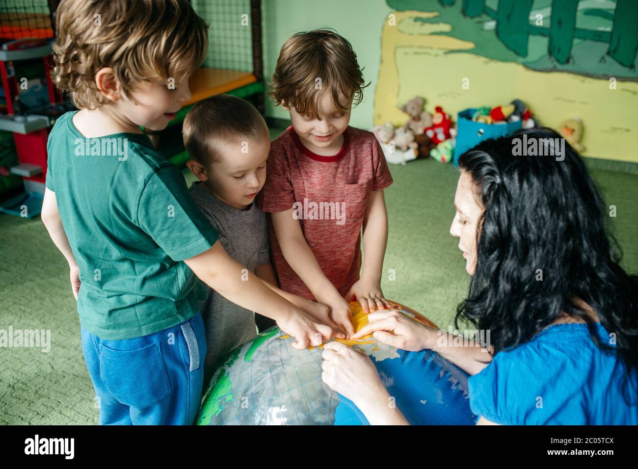 Bambini che imparano circa i paesi con una sfera del globo gonfiabile Foto Stock