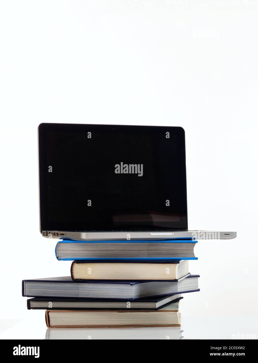 Concetto di e learning. Libri e un computer portatile aperto con schermo nero vuoto isolato su sfondo bianco. Foto verticale, spazio per la copia, modello Foto Stock