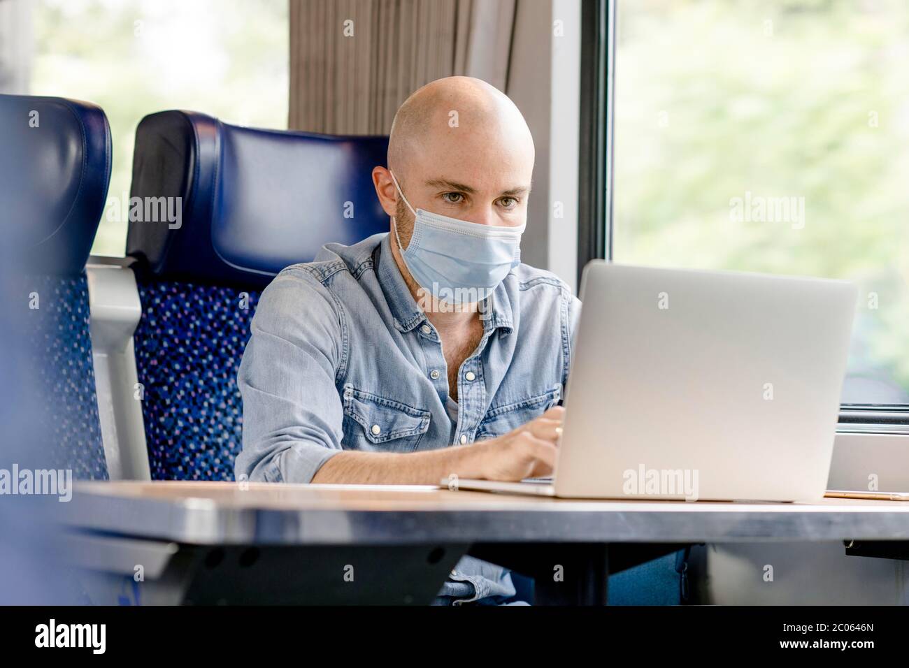 Treno con maschera protettiva per la bocca, uomo che lavora su un computer portatile, Germania Foto Stock