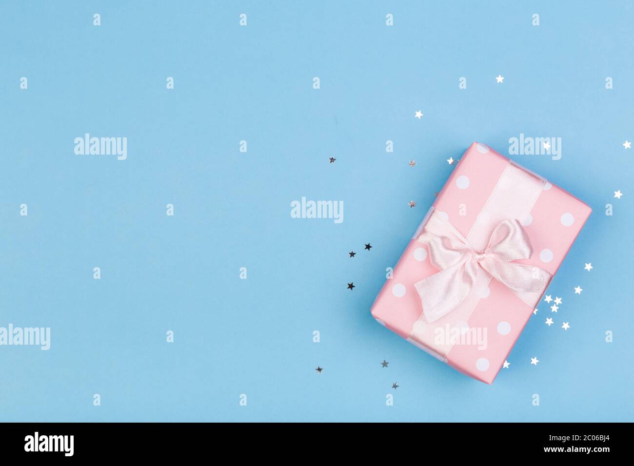 Confezione regalo o regalo e stelle confetti su un tavolo blu dall'alto. Composizione piatta per compleanno, giorno delle madri o matrimonio. Foto Stock