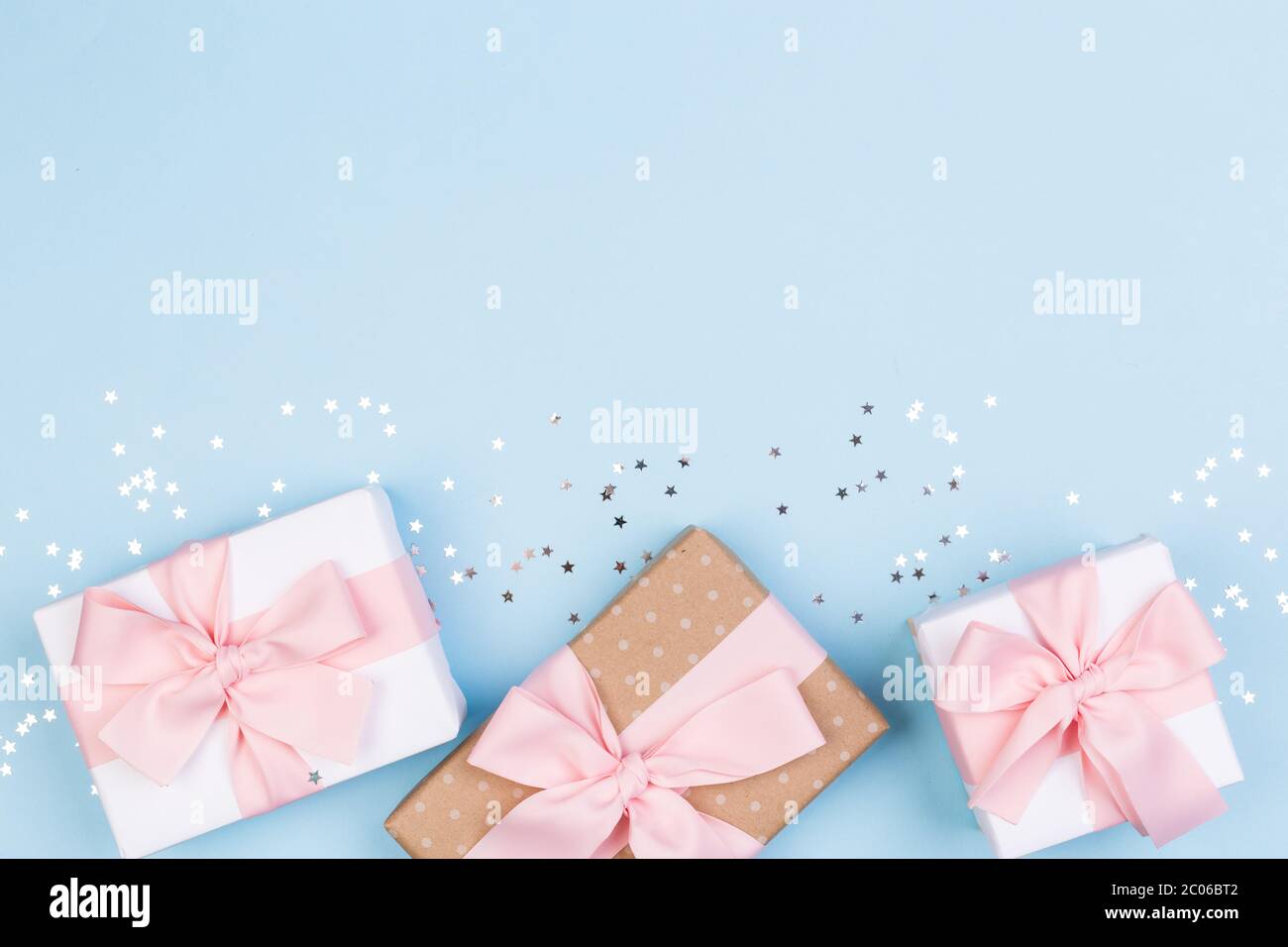 Confezione regalo o regalo e stelle confetti su un tavolo blu dall'alto. Composizione piatta per compleanno, giorno delle madri o matrimonio. Foto Stock