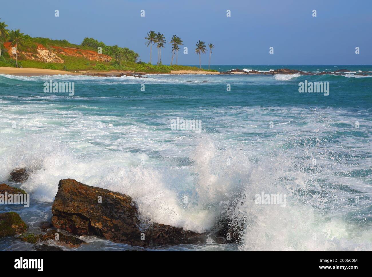 Onde che si infrangono sulle rocce della costa tropicale Foto Stock