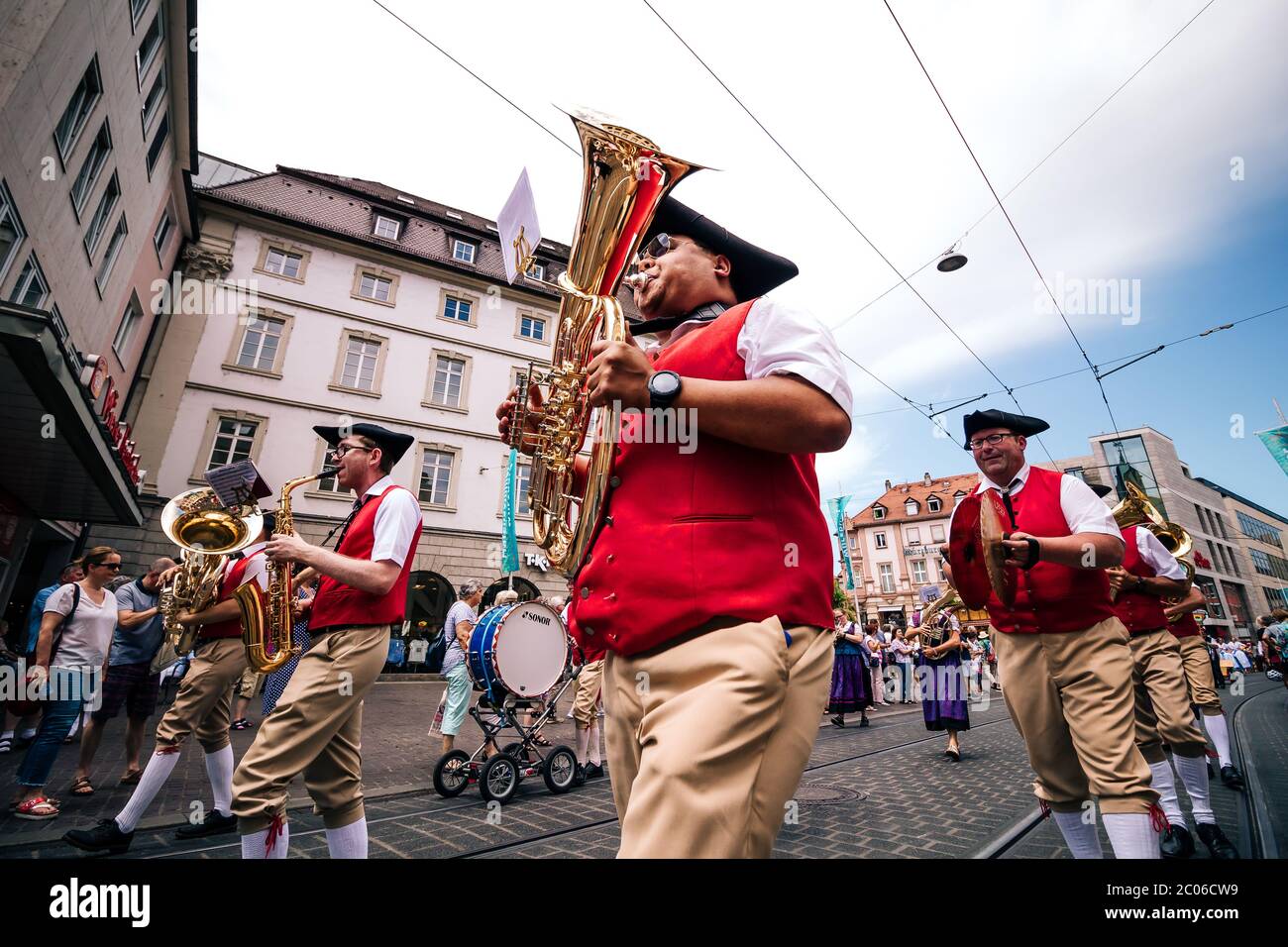 Musicisti con il tradizionale ottone baritono tedesco in tipico costume folk rosso alla sfilata estiva di apertura della fiera Kiliani in Baviera - Germania. Foto Stock