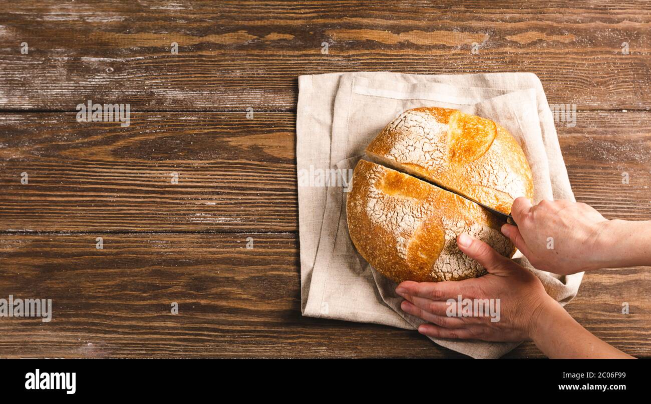 Donna tiene in mano una pagnotta di pane fresco affettato di fondo rustico. Il concetto di cottura di dieta fatta in casa senza Foto Stock