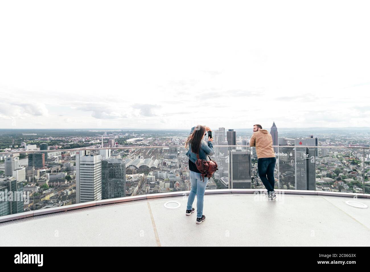 Coppia turistica che scatta foto e ammira la splendida vista dello skyline in un sabato pomeriggio soleggiato dalla cima della Torre principale di Francoforte sul meno. Foto Stock