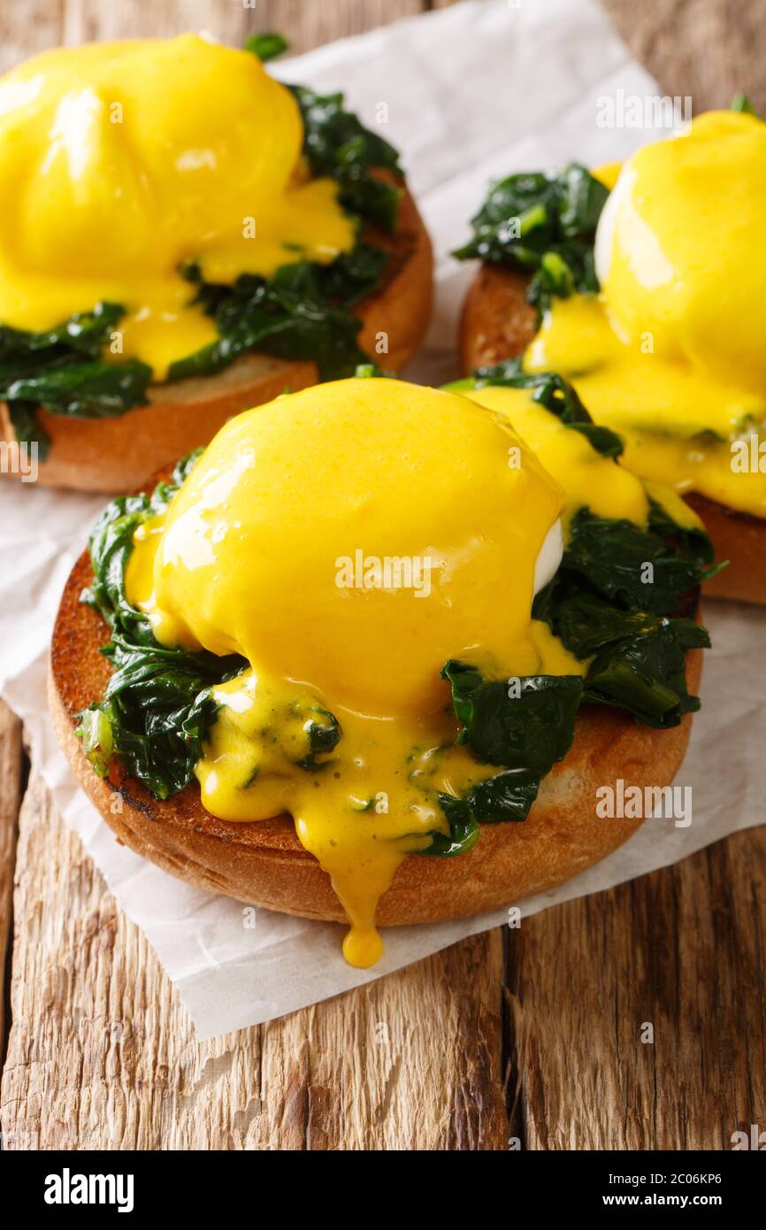 Uova fiorentine a base di uova in camicia con spinaci e salsa di hollandaise su pane da vicino sul tavolo. Verticale Foto Stock