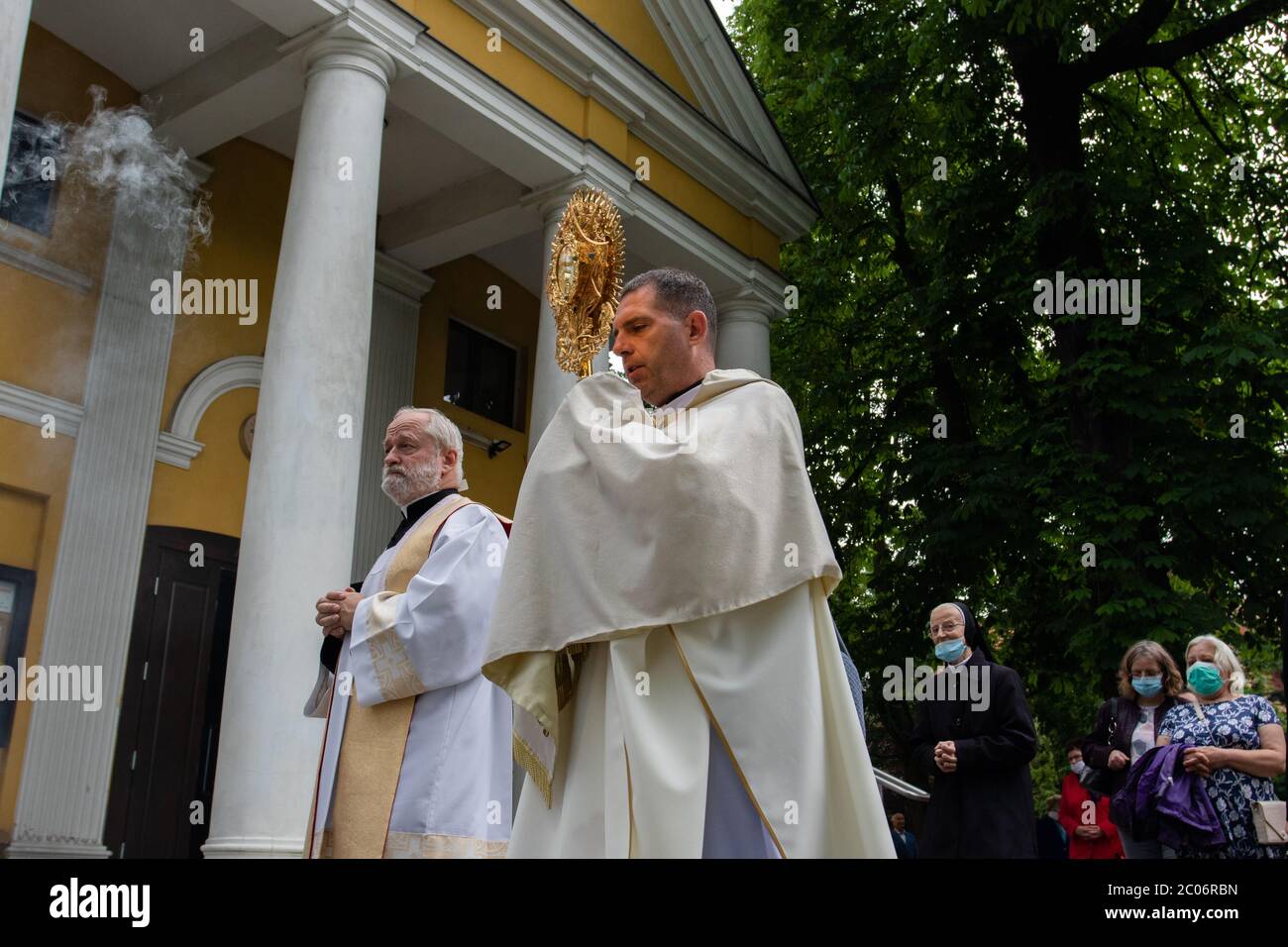 Il sacerdote, visto nella parrocchia della Beata Vergine Maria di Czestochowa, in via Kochanowskiego, durante la processione.Festa del corpo e del sangue di Cristo (Corpus Christi) È una festa dedicata alla venerazione del corpo e del sangue di Cristo, in cui il pane e il vino si trasformano durante l'Eucaristia secondo la fede cristiana. Secondo la tradizione, in questo giorno si organizza una solenne processione per le strade della Chiesa cattolica. In Polonia, questo giorno è una festa pubblica. Quest'anno, molti partecipanti alla processione indossavano maschere mediche, tra cui server di altare e monache. Foto Stock