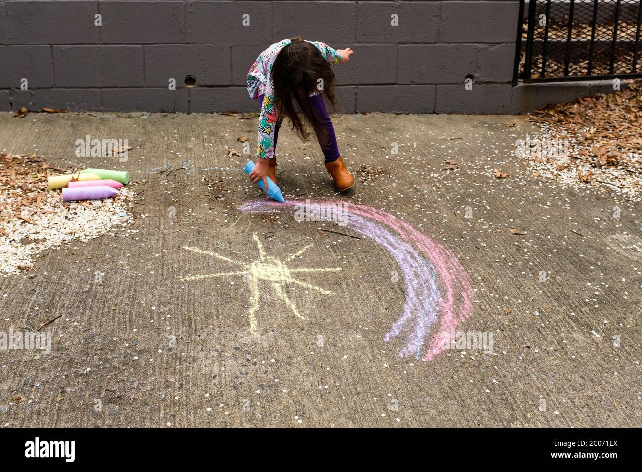 Bambina che disegna arcobaleno con gesso Foto Stock