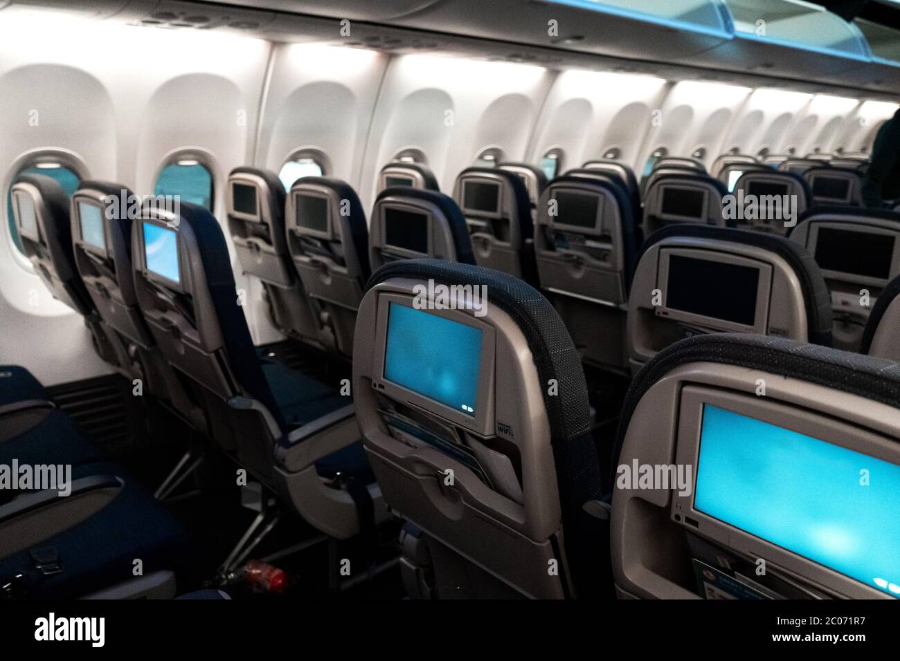 L'interno dell'aeromobile. Cabina vuota dell'aereo. File di sedili  passeggeri con schermi nei poggiatesta Foto stock - Alamy