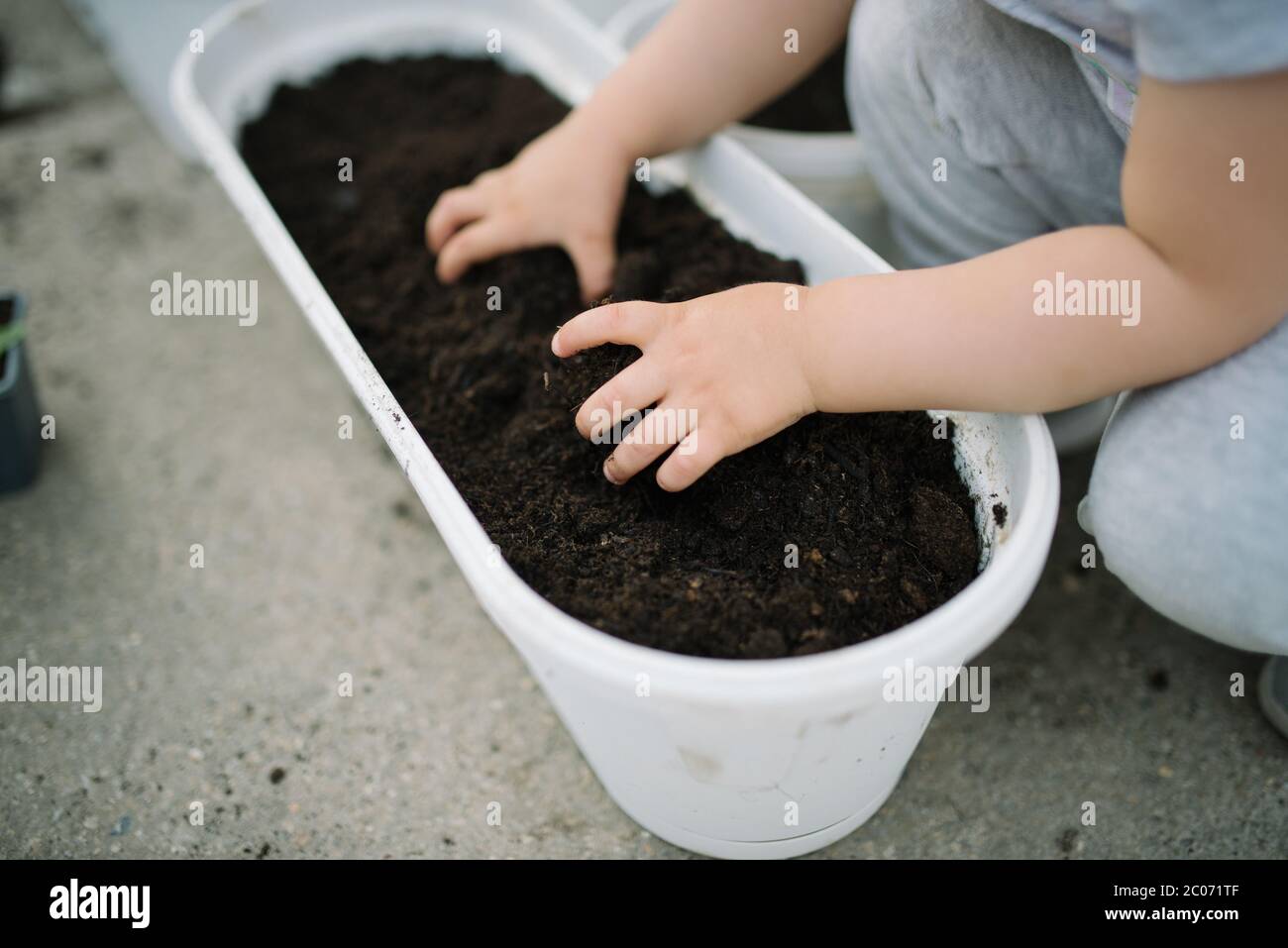 Una bambina si diverte in giardino e tiene un terreno da giardino Foto Stock