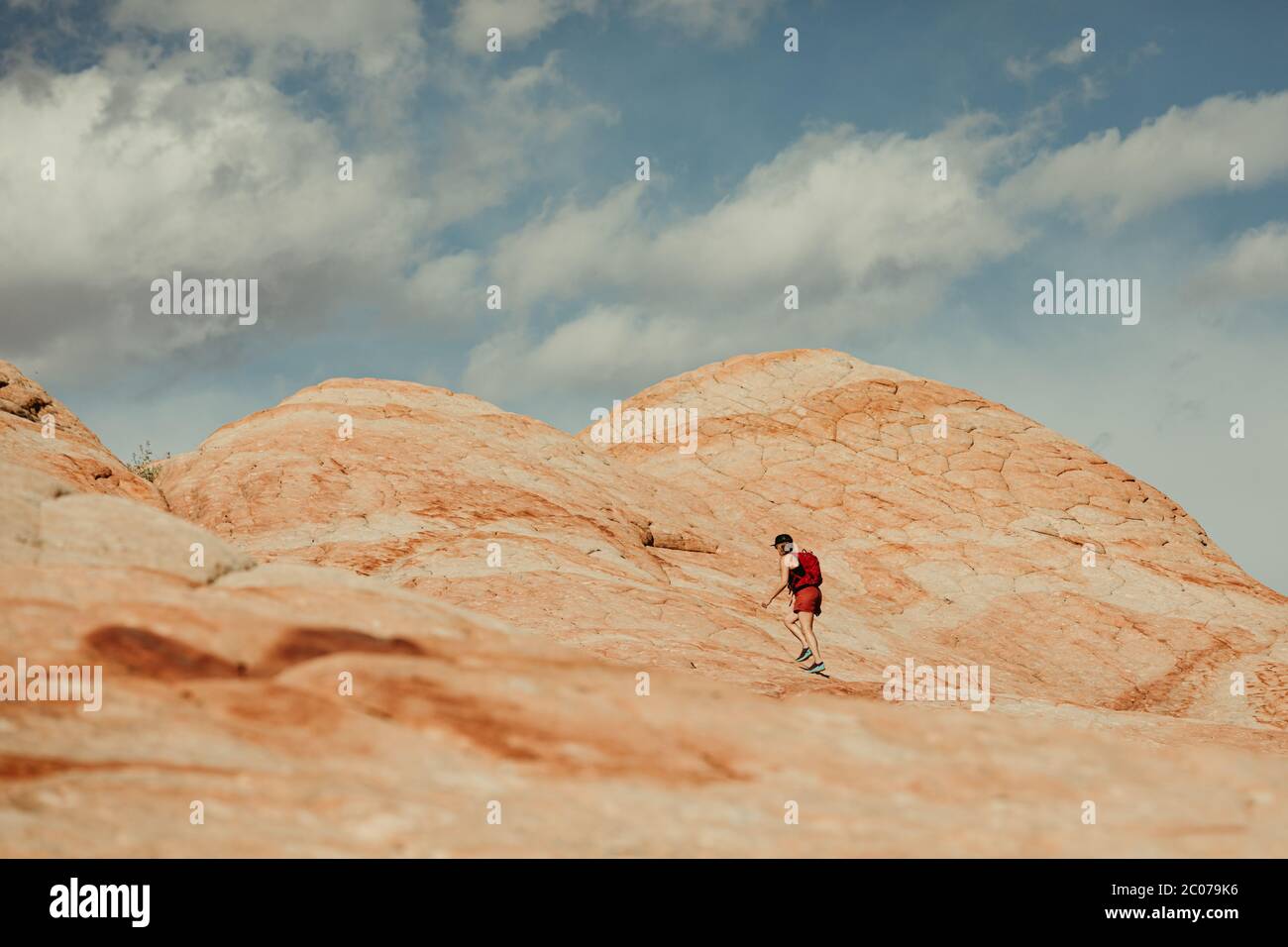 donna escursionista vestito di rosso cammina su rosso e bianco pietrificato duna di sabbia Foto Stock