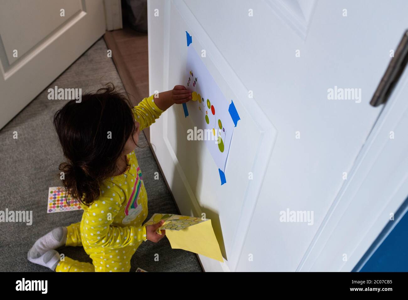 Bambina che gioca con gli adesivi interni Foto Stock