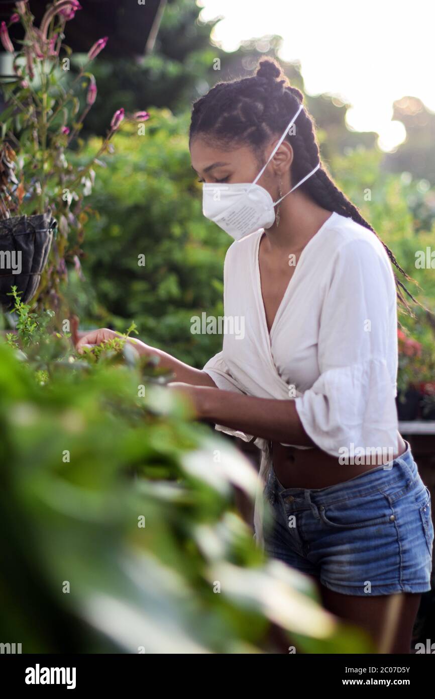 Giovane donna che fa giardinaggio in maschera facciale Foto Stock