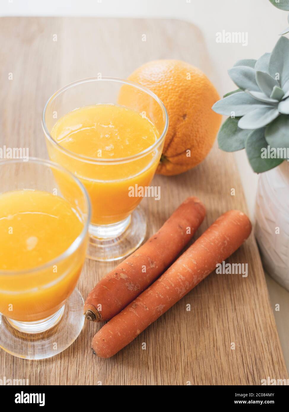 succo d'arancia con arancia, carote e una pianta Foto Stock