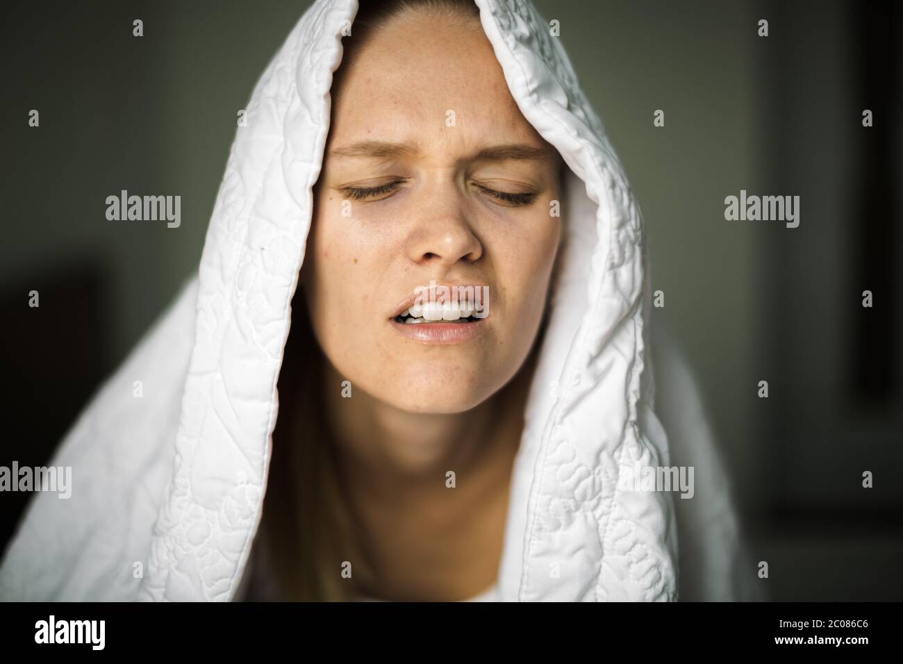 Un adulto stanco e assonnato a letto che ha problemi di sonno nel mezzo della notte con il cuscino e la coperta che copre la sua testa. Privazione del sonno. Foto Stock