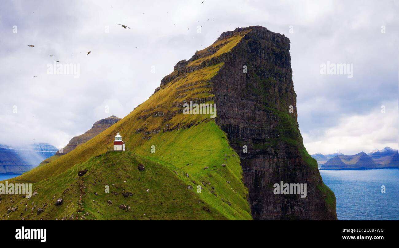 Piccolo faro situato sull'isola di Kalsoy con i gabbiani che volano, Isole Faroe Foto Stock