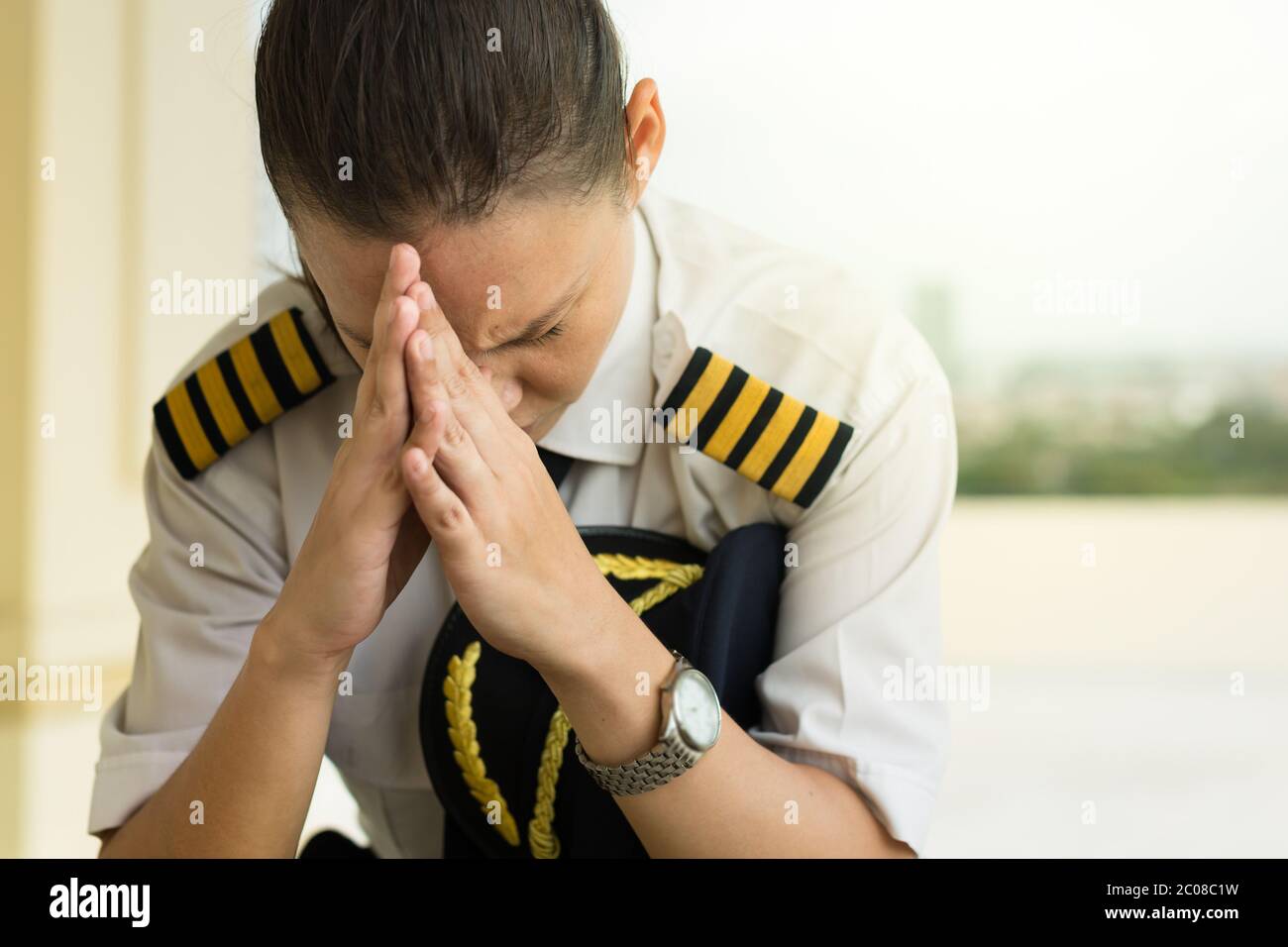 Una pilota femminile seduto all'aeroporto che ha una brutta giornata, preoccupato e sofferente di ansia. Foto Stock