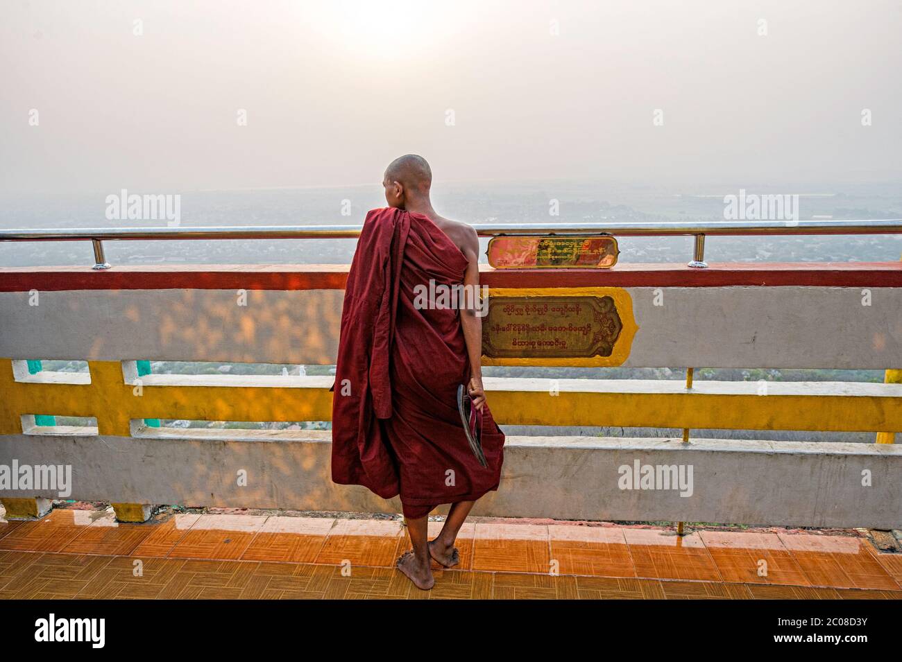 Un giovane monaco buddista si affaccia sulla pagoda su Taung Pyae sulla collina di Mandalay. Mandalay Myanmar (Birmania) Foto Stock